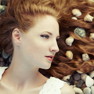 Beautiful young woman with unusual hairstyle on beach. Fashion photo